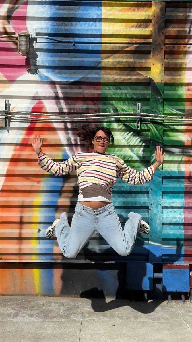 Mandy qui saute de joie devant une fresque colorée