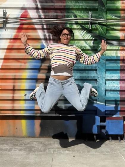 Mandy en train de sauter devant une fresque colorée